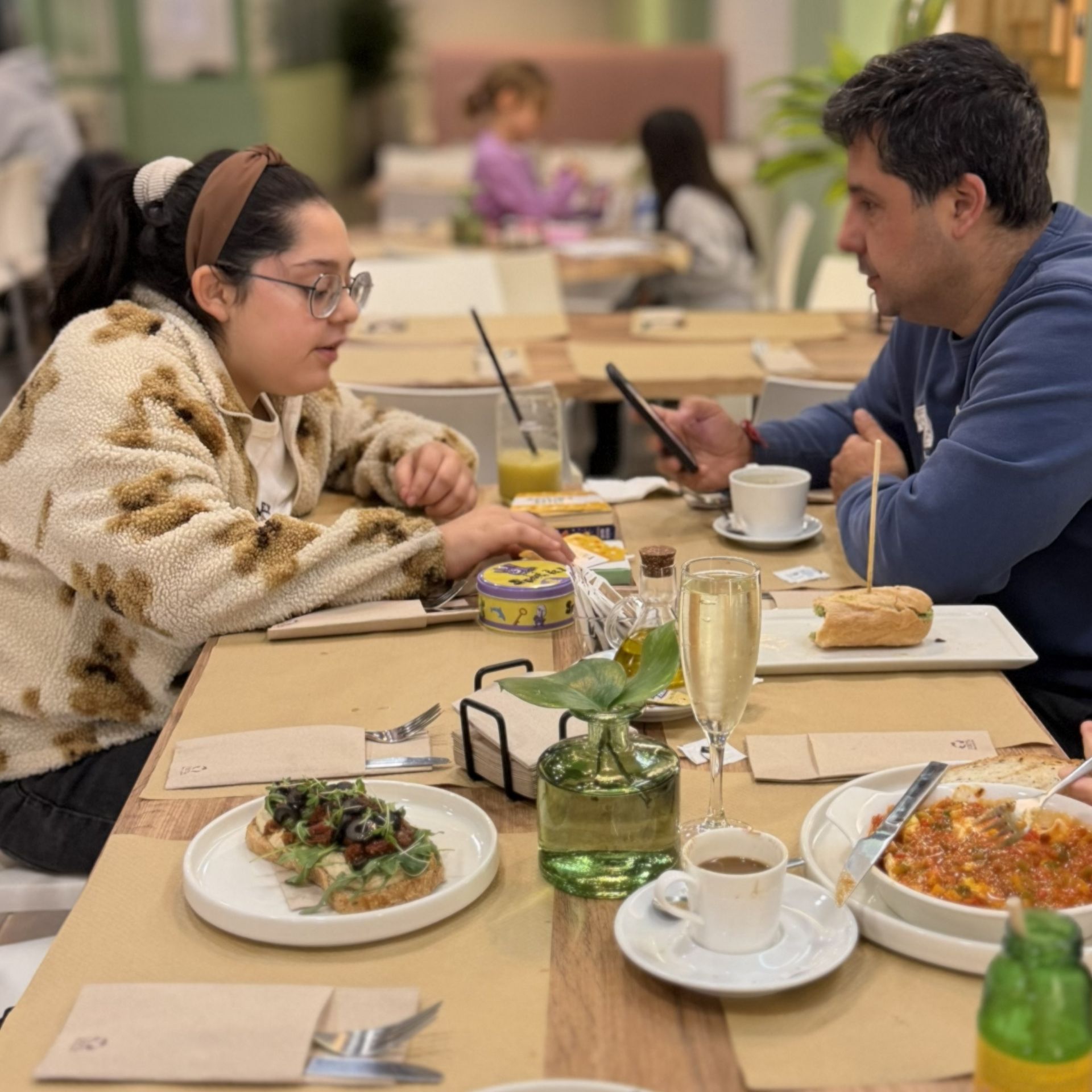 Clientes desayunando en Gato Blanco, con bocadillo, café y zumo natural sobre la mesa