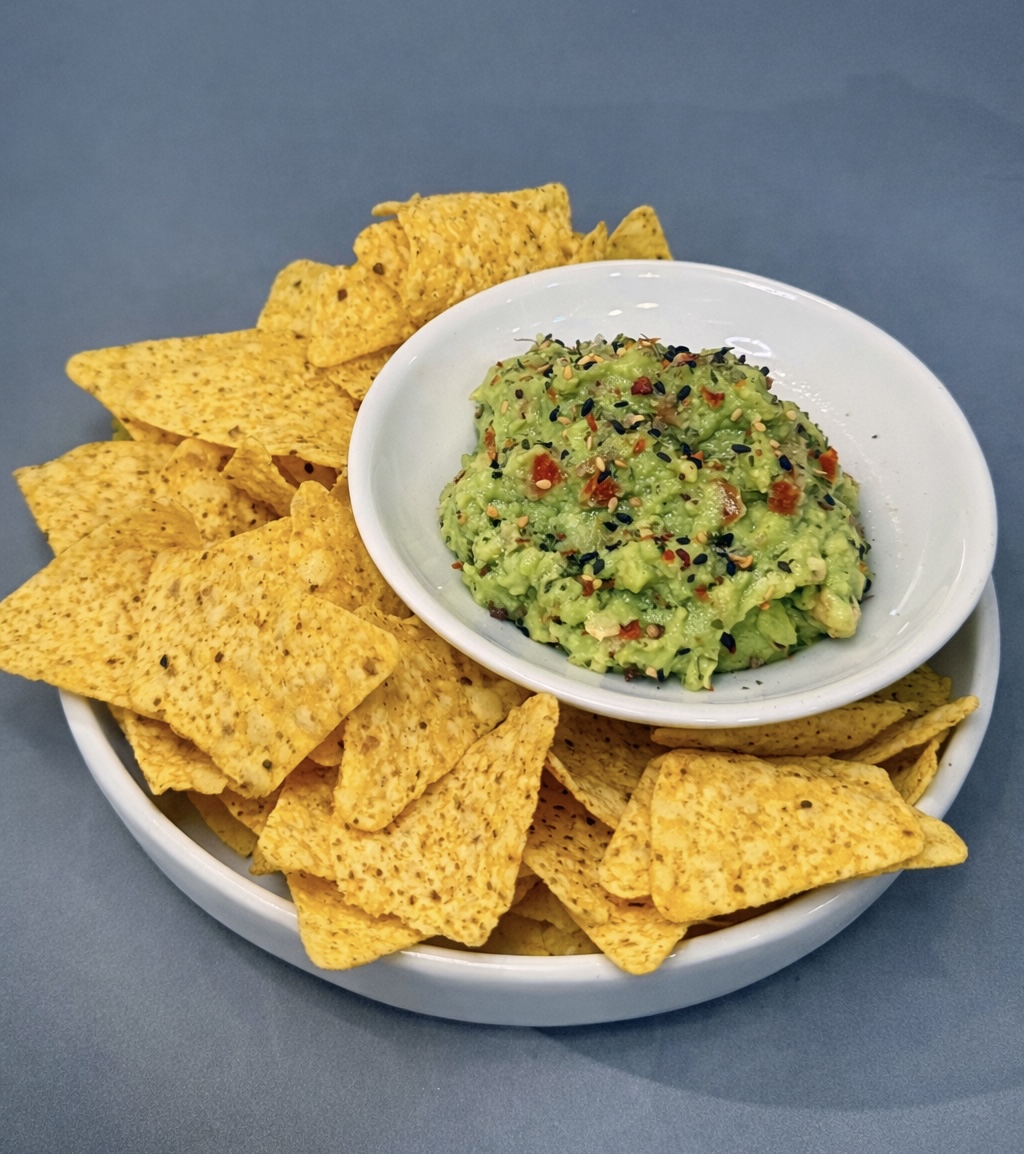 Guacamole con semillas y nachos de maíz en un plato blanco, para compartir en un brunch sin gluten