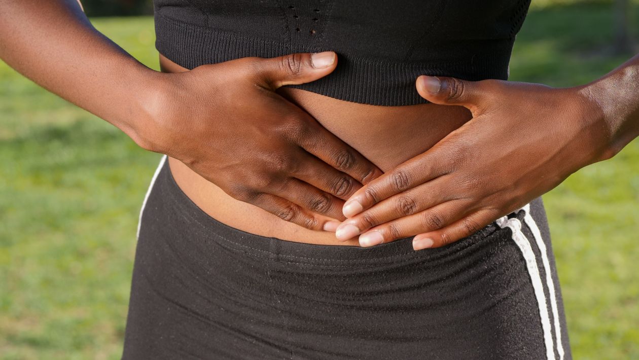 Mujer con las manos sobre el abdomen, gesto de las molestias digestivas que produce la celiaquía
