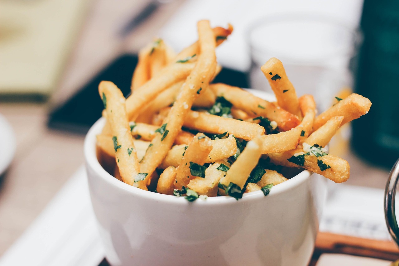 White bowl of french fries with chopped parsley
