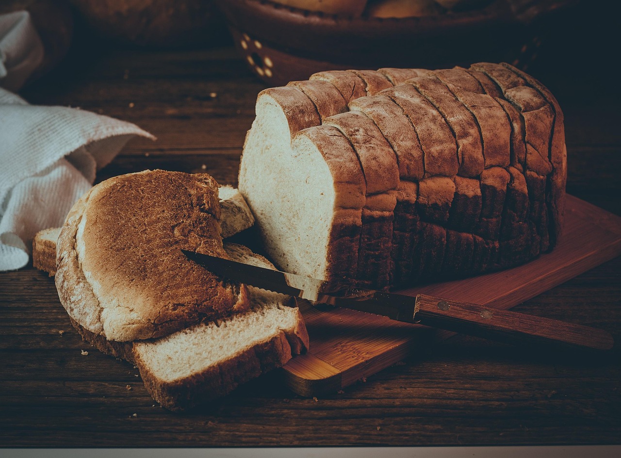 Pan de molde cortado en rebanadas sobre una tabla de madera, un alimento con gluten